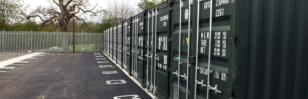 Row of green storage containers beside numbered bays